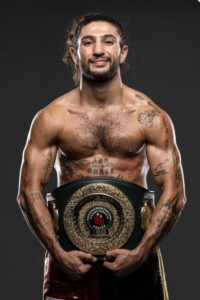 Razor Ali holding his boxing belt in a studio portrait