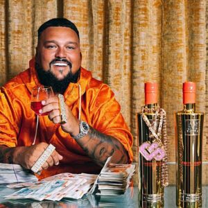 Charlie Sloth wearing an orange shirt beside Au Vodka bottles